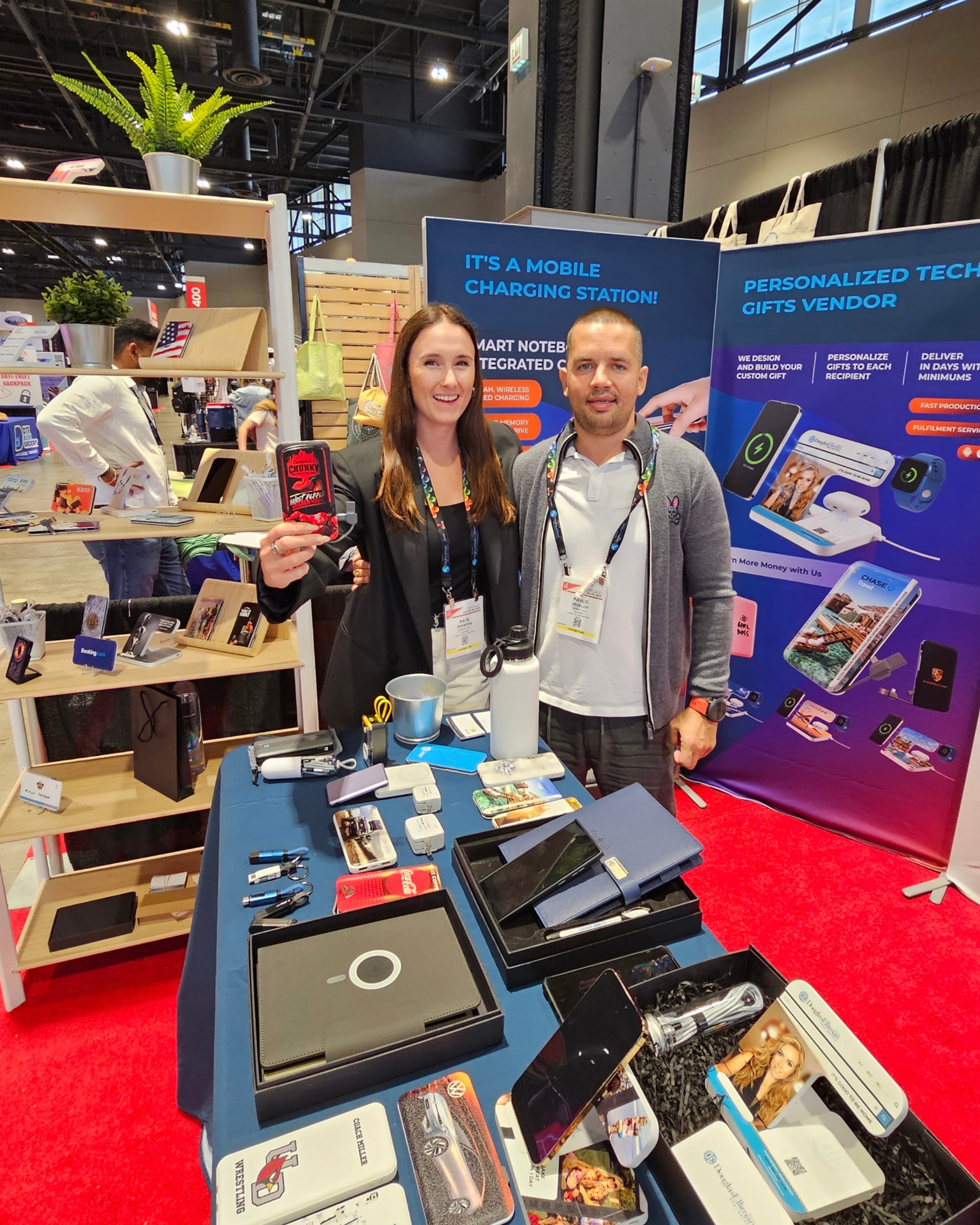TrendSet Promo Supply team at the company booth during an ASI Show, presenting custom branded power banks and wireless charging products